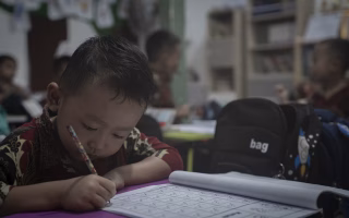 Young child focused on writing in a classroom setting