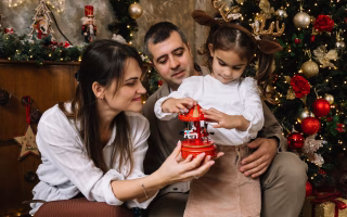 Family celebrating Christmas with a child playing near a decorated tree.