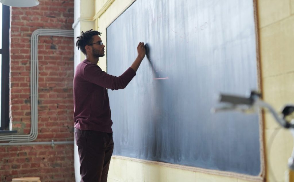 Teacher Writing On Blackboard