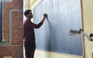 Teacher Writing On Blackboard